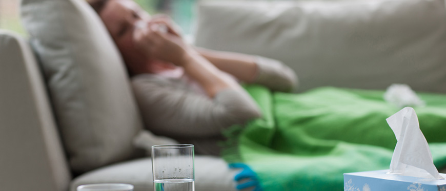 Woman blowing nose, lying sick on sofa