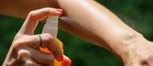 Woman spraying bug deterrent on arm